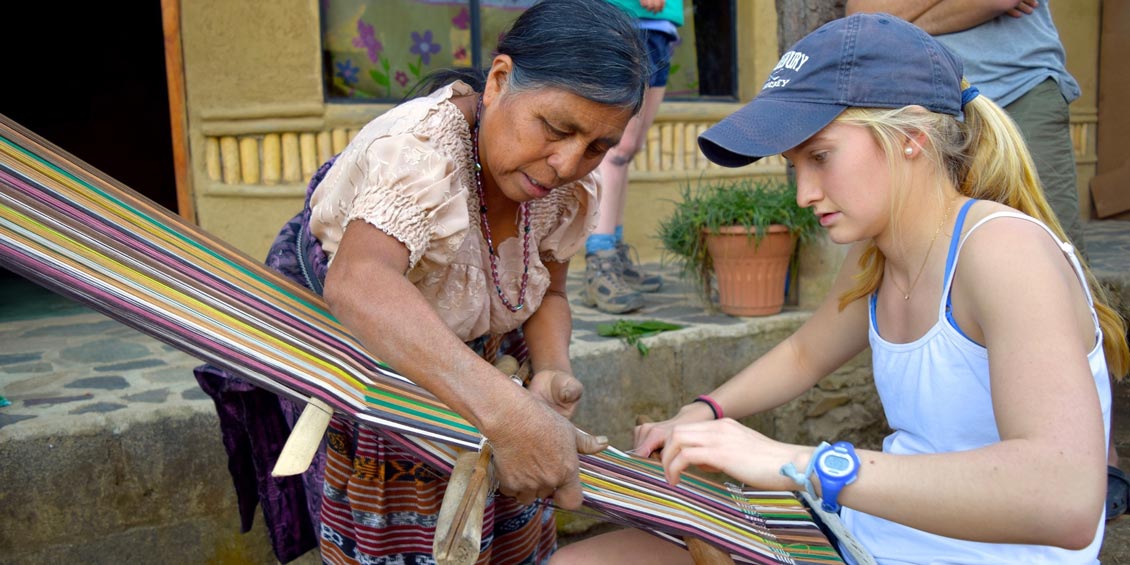 a student working with a woman using colorful threads
