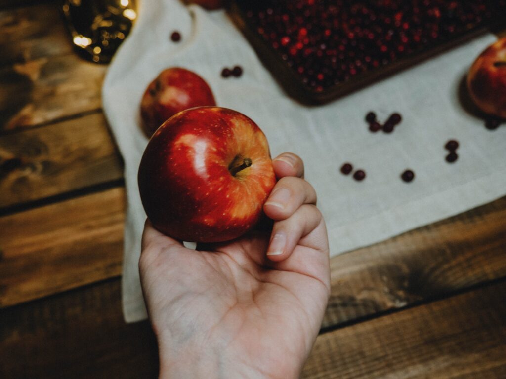 Photo of a person holding an apple, contemplating what natural apple recipes to make. 