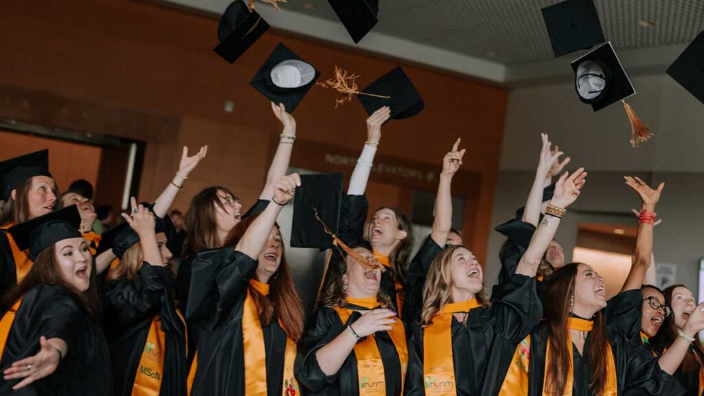 graduates throwing caps into air