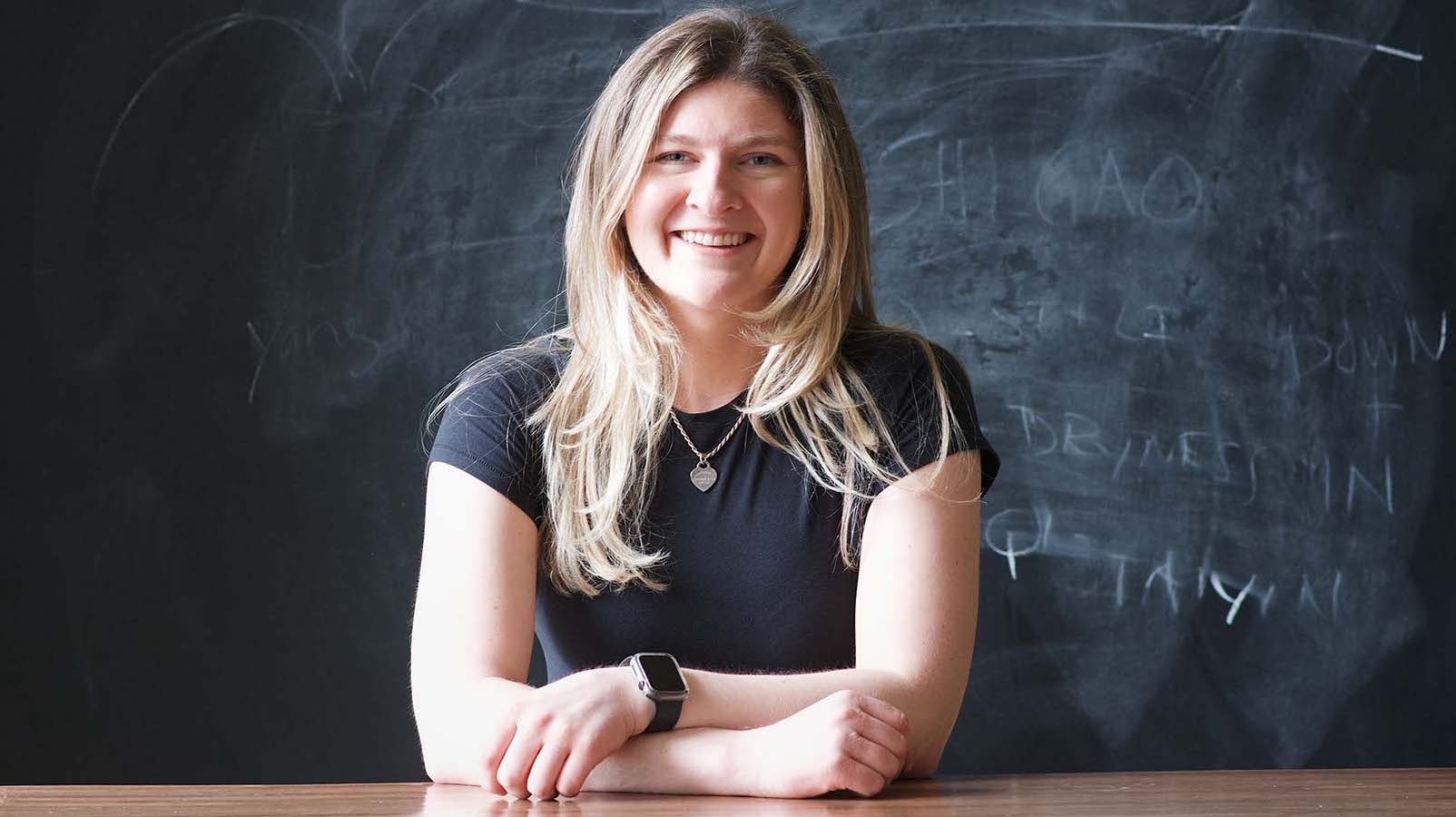 Payton Follestad sitting at table in front of chalkboard