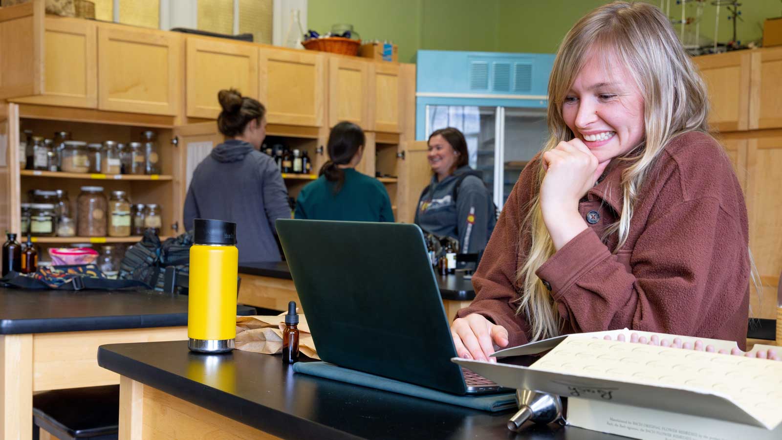 Woman in classroom smiling at computer
