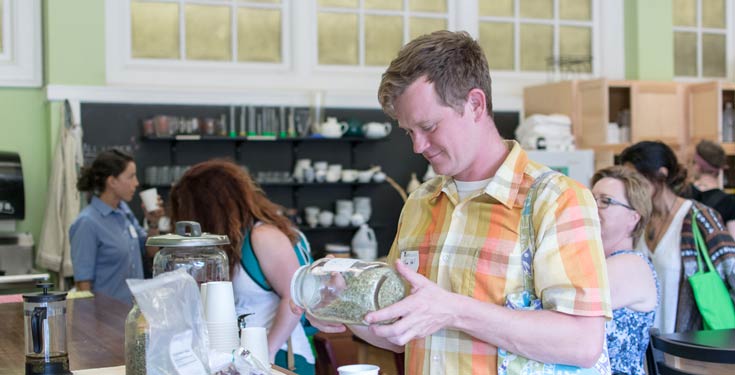 Smiling man holding jar of herbs