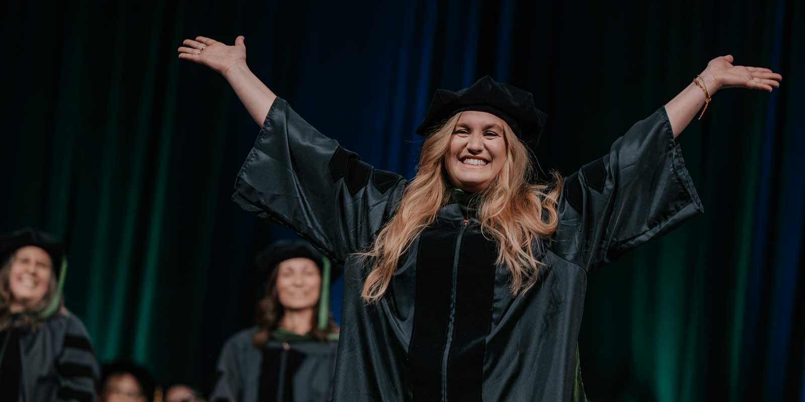 graduating student with hands in the air