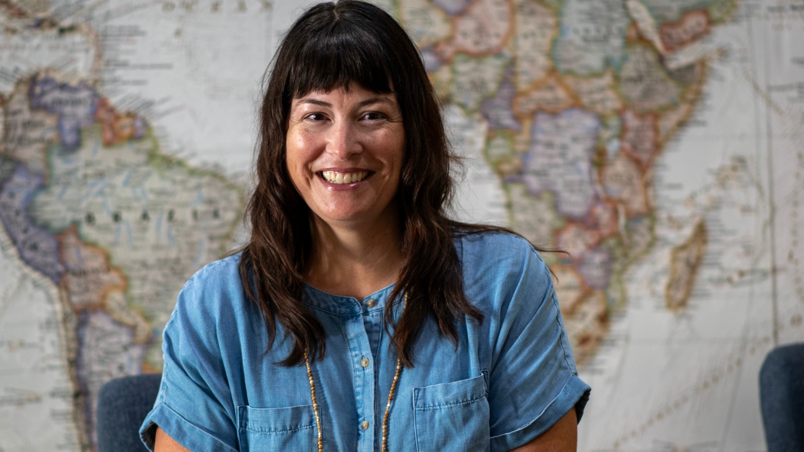 Rebecca Bohlin, an NUNM admissions counselor smiling for a photo with a world map in the background