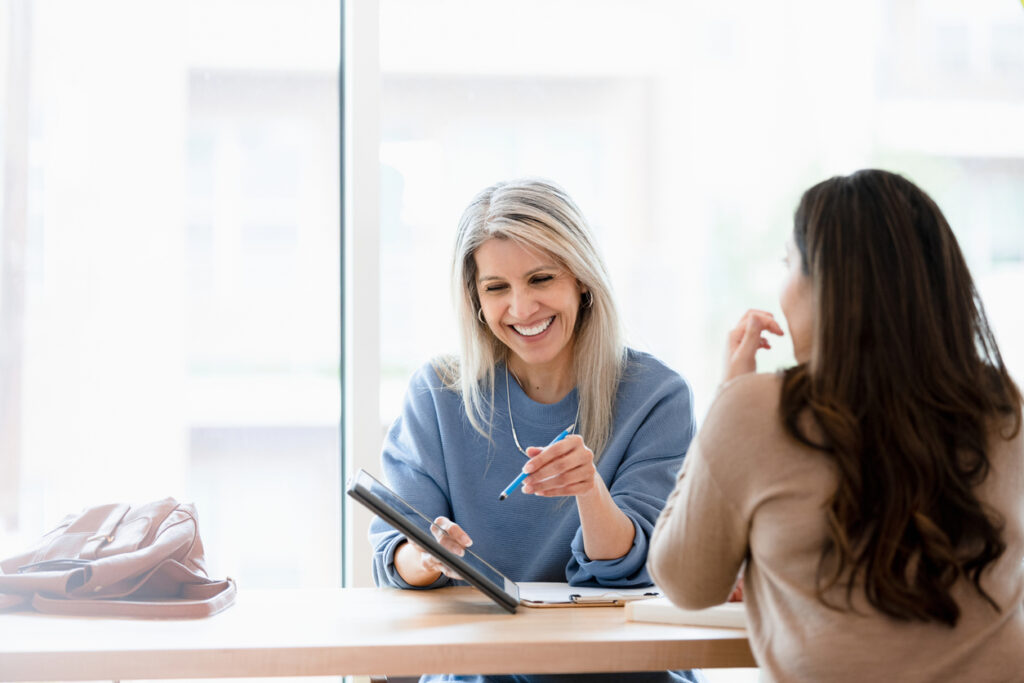 A female doctor of naturopathic medicine sits at a desk across from their patient, happily discussing her test results.