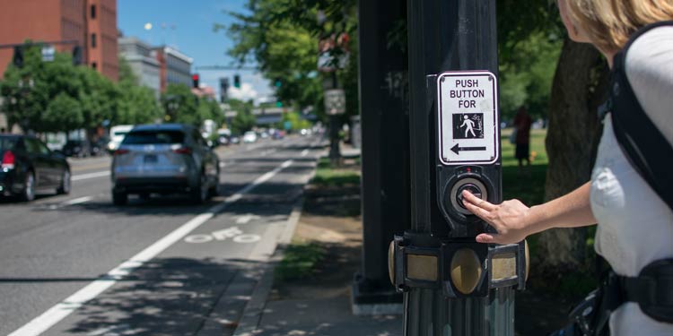 Women pressing a cross walk button at a street intersection in Portland