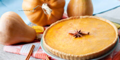 Homemade spicy pumpkin pie with cinnamon on a table with pumpkins at background