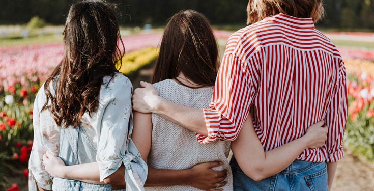 Three back facing woman with arms around each other's waists